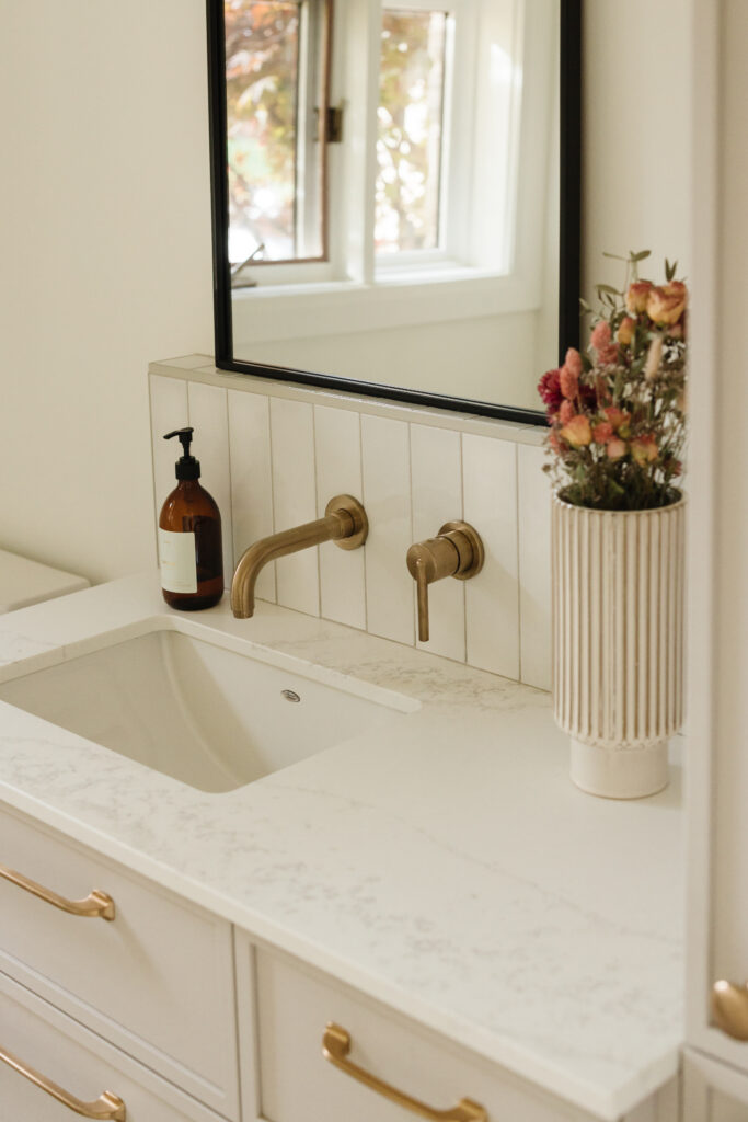Salle d’eau élégante sur mesure avec meuble flottant, robinetterie dorée, miroir arrondi et palette douce et chaleureuse
