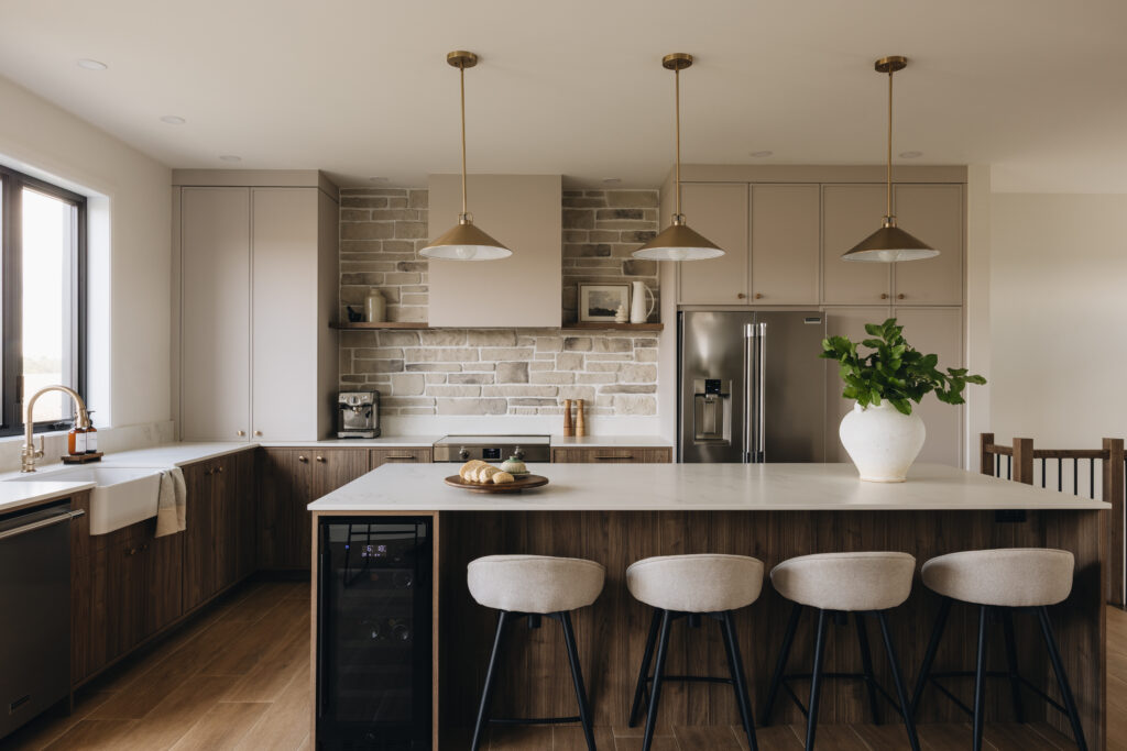 Cuisine sur mesure chaleureuse avec îlot central, armoires aux tons neutres, effet bois foncé, maçonnerie intégrée et comptoir en Dekton