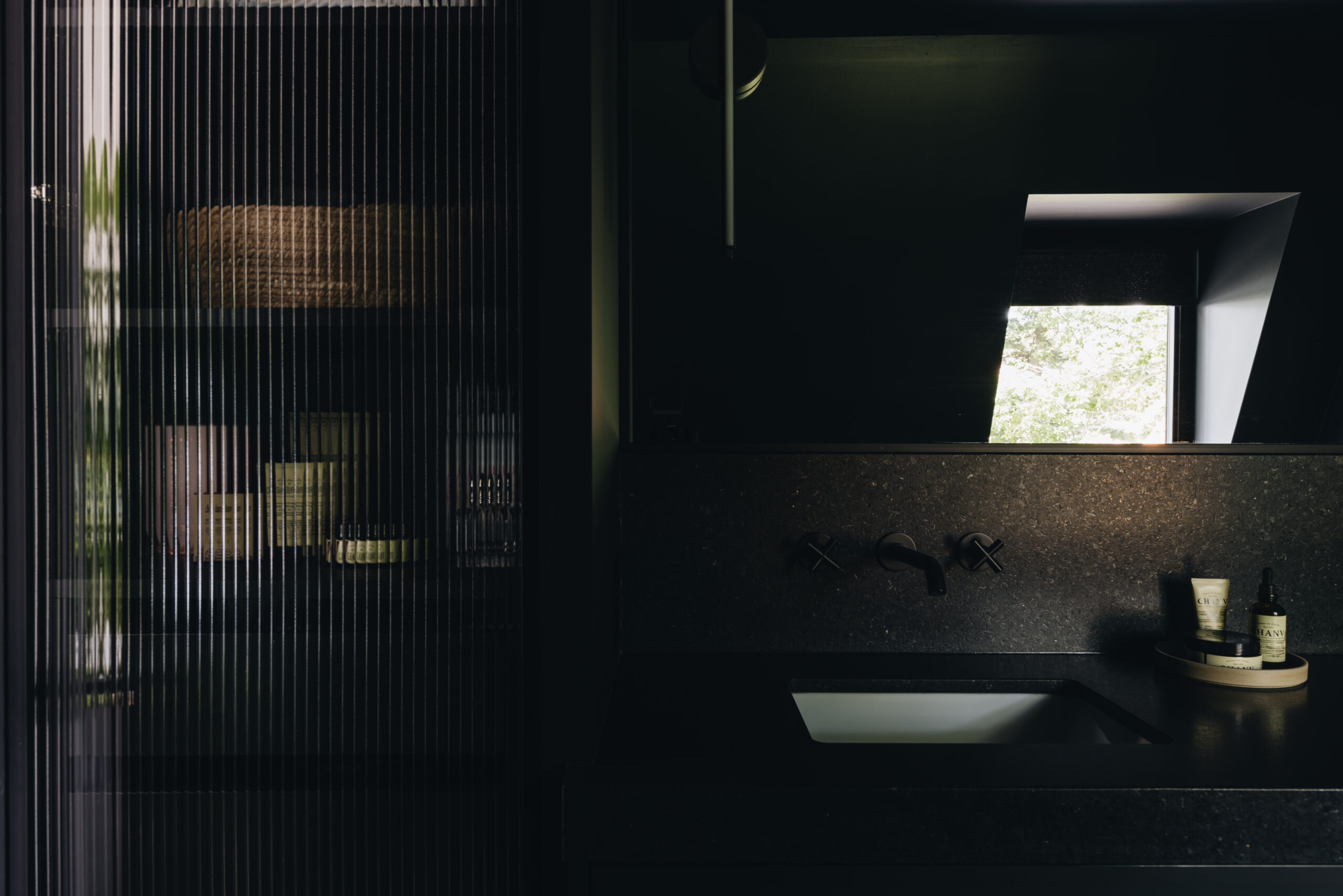 Salle de bain sur mesure au design foncé et enveloppant, avec vanité noire, comptoir en granit Cambrian et ambiance spa raffinée