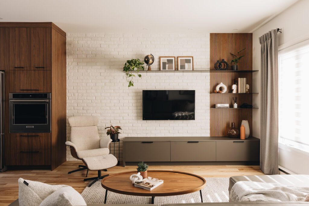 Salon sur mesure avec unité murale intégrée, mur de brique blanche, panneaux de bois latté et ambiance chaleureuse contemporaine