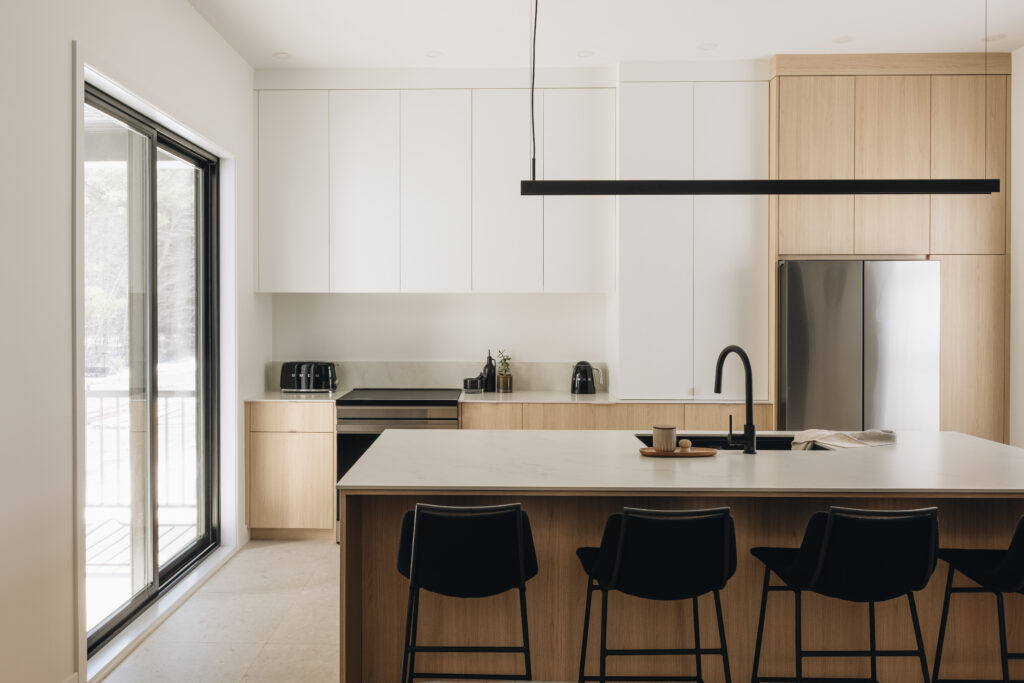 Cuisine moderne au design épuré et minimaliste, baignée de lumière naturelle. Bois clair, lignes droites et îlot central signés Espaces Rubic.