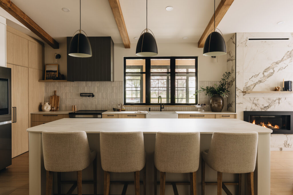 Cuisine chaleureuse sur mesure avec grand îlot aux coins arrondis, hotte rainurée, poutres apparentes et ambiance conviviale