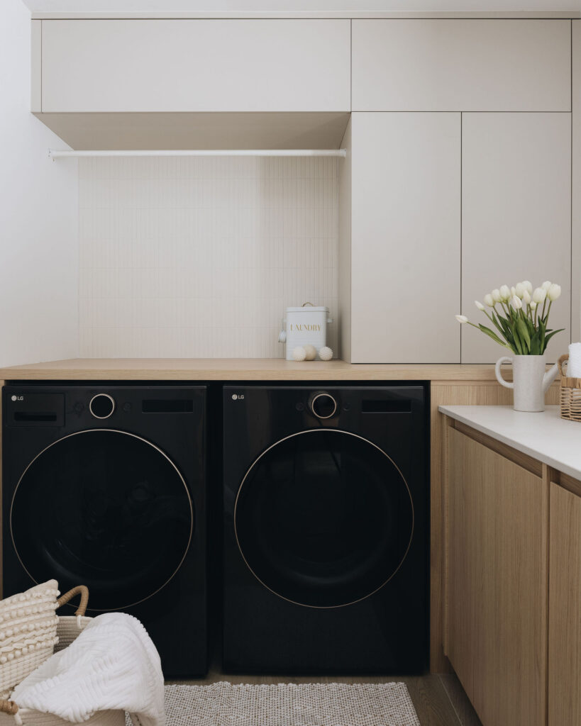 Buanderie minimaliste sur mesure avec armoires claires, électroménagers intégrés, rangement fonctionnel et ambiance lumineuse