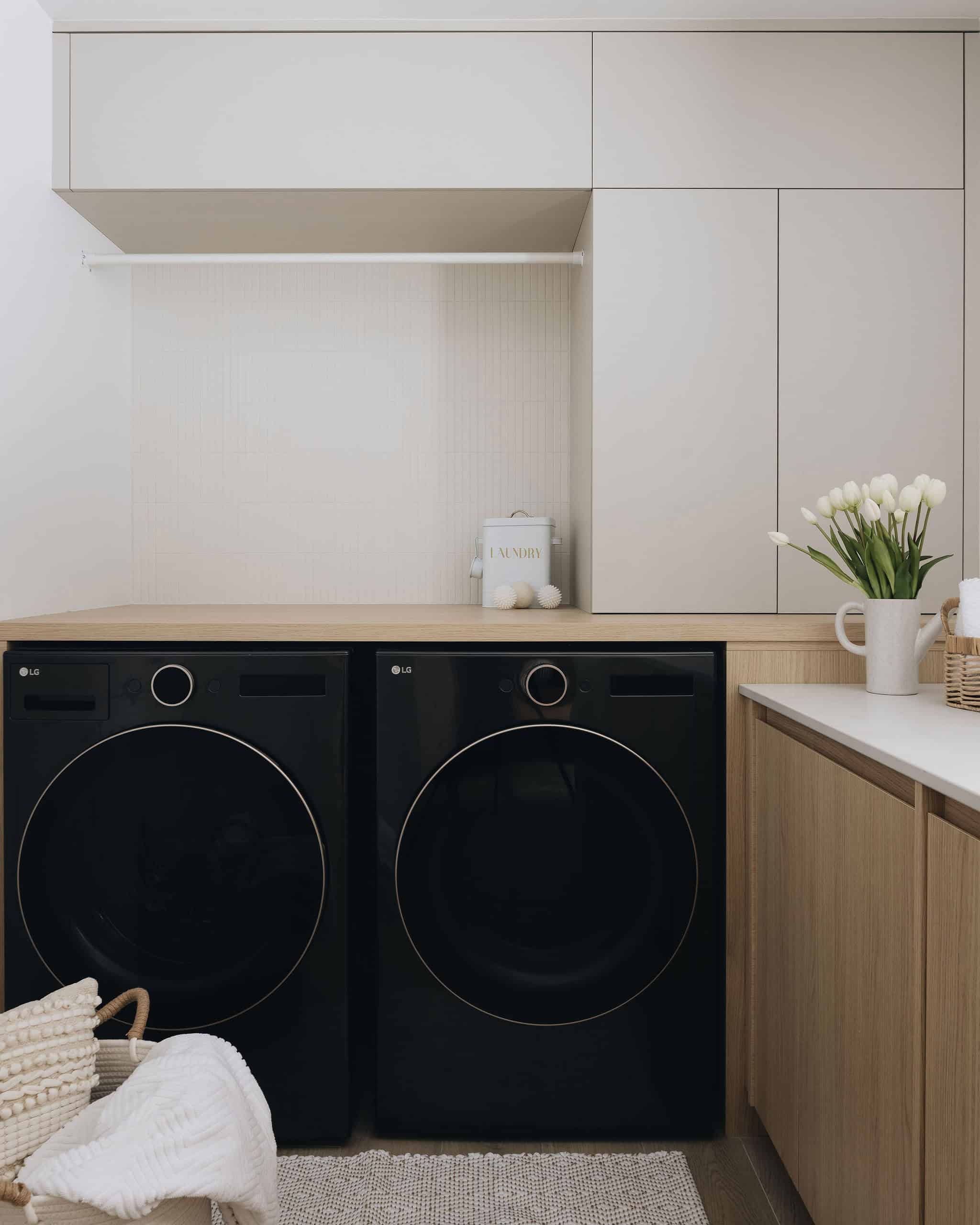 Buanderie minimaliste sur mesure avec armoires claires, électroménagers intégrés, rangement fonctionnel et ambiance lumineuse