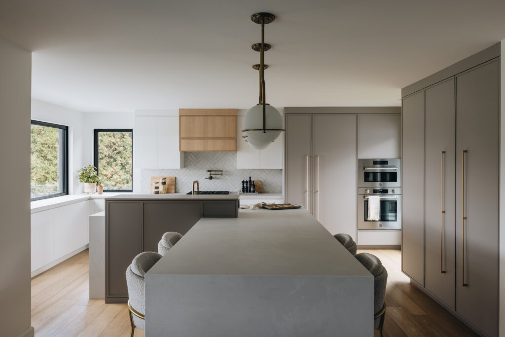 Cuisine moderne sur mesure avec îlot sculptural, armoires pleine hauteur, lignes épurées et lumière naturelle abondante