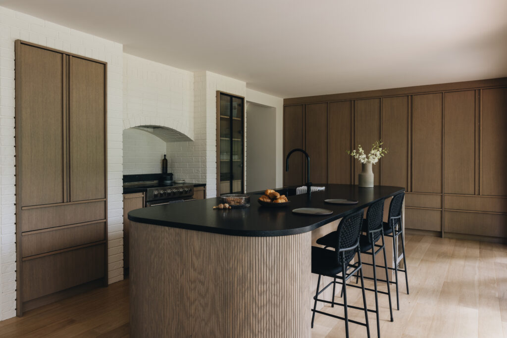 Cuisine japandi sur mesure avec îlot arrondi, armoires en chêne blanc, granit noir Cambrian et design épuré et chaleureux