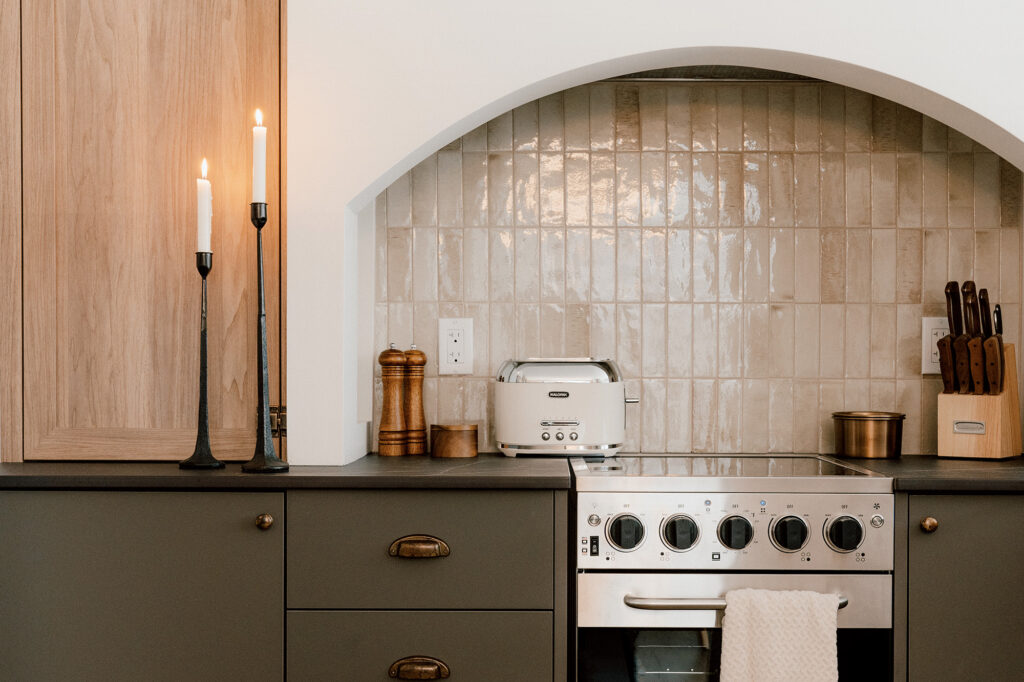 Cuisine de chalet sur mesure avec armoires en bois clair, caissons gris foncés et alcôve en arche au style rustique raffiné