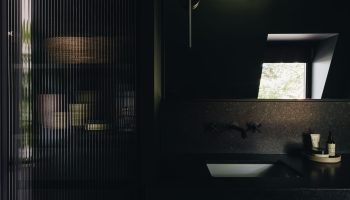 Salle de bain sur mesure au design foncé et enveloppant, avec vanité noire, comptoir en granit Cambrian et ambiance spa raffinée