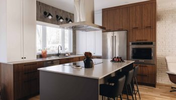 Cuisine contemporaine sur mesure avec îlot central, armoires en bois foncé, électroménagers encastrés et design chaleureux