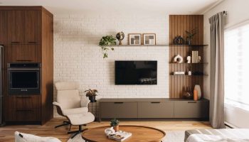 Salon sur mesure avec unité murale intégrée, mur de brique blanche, panneaux de bois latté et ambiance chaleureuse contemporaine