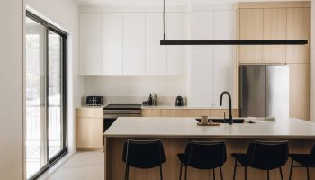 Cuisine moderne au design épuré et minimaliste, baignée de lumière naturelle. Bois clair, lignes droites et îlot central signés Espaces Rubic.