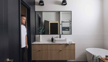 Salle de bain minimaliste sur mesure avec vanité en bois clair, accents noirs, baignoire autoportante et design épuré