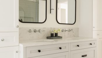 Salle de bain classique sur mesure avec vanité grise, miroirs arqués, rangement intégré et ambiance douce et lumineuse