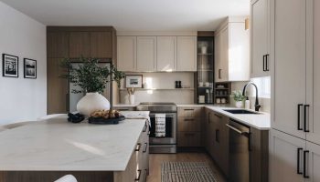 Cuisine contemporaine sur mesure avec îlot central spacieux, armoires en bois naturel et beige, comptoir en pierre et design chaleureux