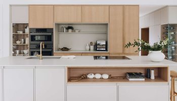 Cuisine minimaliste sur mesure avec armoires en bois clair et blanc mat, îlot central et design contemporain épuré