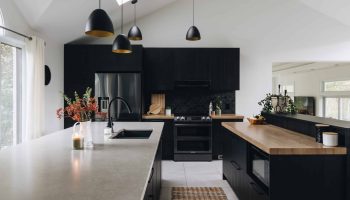 Cuisine noire sur mesure au style industriel avec plafond cathédrale, double îlot et comptoir en quartz effet béton