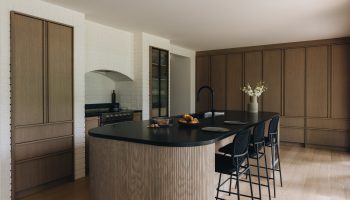 Cuisine japandi sur mesure avec îlot arrondi, armoires en chêne blanc, granit noir Cambrian et design épuré et chaleureux