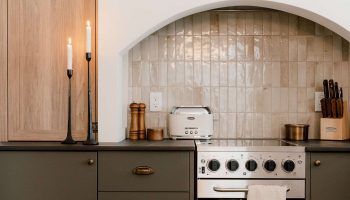 Cuisine de chalet sur mesure avec armoires en bois clair, caissons gris foncés et alcôve en arche au style rustique raffiné